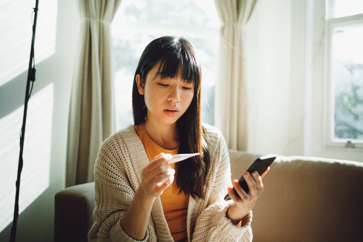 person checking a thermometer while holding a phone 
