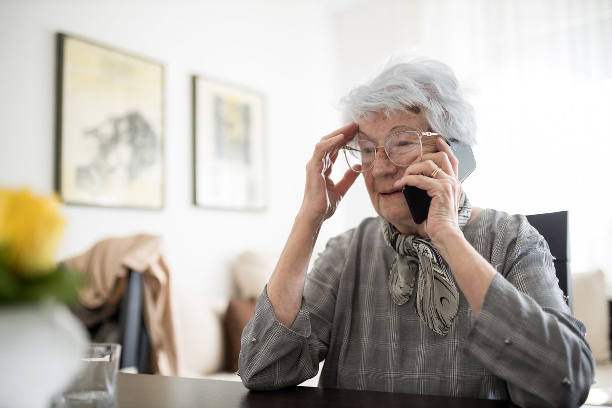 a person holding their eyeglasses near their face while talking on the phone