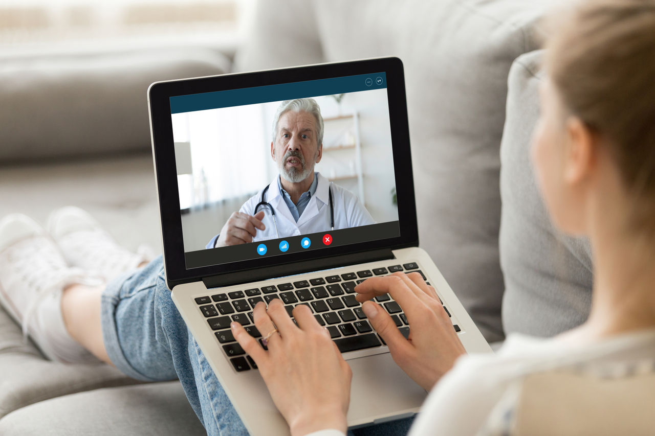 Young woman on her laptop talking to her doctor during a virtual appointment